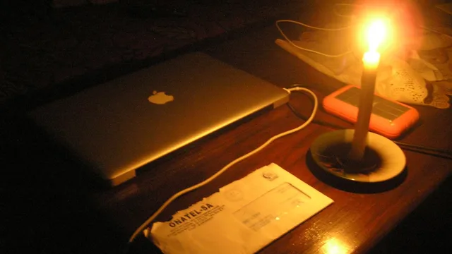 A candle burning on a table next to a laptop during a power cut